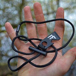 Forest Fundamentals Sidekick firelighting necklace. A hardened steel striker, a ferrocerium rod, and some survival paracord. Shown here in the palm of an open hand.