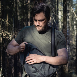 The DD Crosswind Sling bag, shown here diagonally across the front of a person's body, while they close the main compartment.