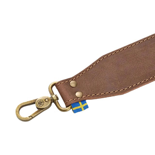 Brown leather axe sling with brass clasps and a Swedish flag label.