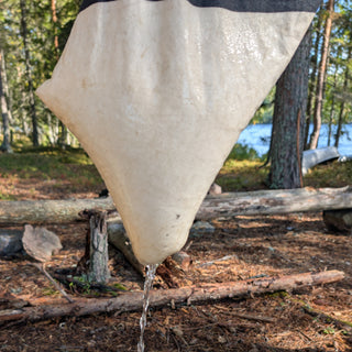 Forest Fundamentals Mill Bank Bag in use in a woodland near a lake, showing the flow of water from the bag.