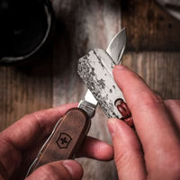 Wazoo Gear Viking Whetstone pendant necklace, natural Arkansas stone, on a leather cord, shown sharpening a knife.