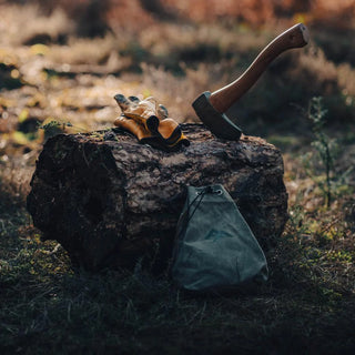 Forest Fundamentals Tinder Pouch, a hand crafted waxed canvas pouch for carrying tinder or anything else! Shown here next to a small log, with an axe and a pair of gloves to give a sense of scale. 